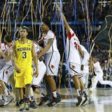 The Louisville Cardinals celebrate as Michigan Wolverines guard Trey Burke (3) leaves the court after Louisville won the NCAA men's Final Fo