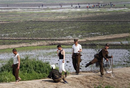 A North Korean soldier (R) throws a stone at a Chinese tourist boat in front of paddy fields on the banks of Yalu River near the North Korea A North Korean soldier (R) throws a stone at a Chinese tourist boat in front of paddy fields on the banks of Yalu River near the North Korea