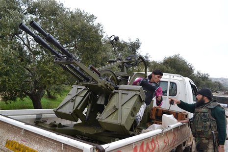 A Free Syrian Army Fighter, on a vehicle mounted with an anti-aircraft artillery weapon, speaks with his comrade before heading to Wadi al-D A Free Syrian Army Fighter, on a vehicle mounted with an anti-aircraft artillery weapon, speaks with his comrade before heading to Wadi al-D