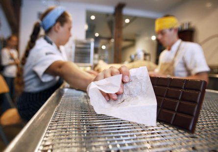 Stephanie Ault, an employee of Mast Brothers Chocolate, reaches for a chocolate bar to wrap at the company's factory in the Brooklyn borough Stephanie Ault, an employee of Mast Brothers Chocolate, reaches for a chocolate bar to wrap at the company's factory in the Brooklyn borough