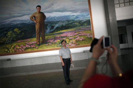 A Chinese visitor poses for a picture next to a portrait of then North Korean leader Kim Jong-il at an auditorium in Rason city, northeast o A Chinese visitor poses for a picture next to a portrait of then North Korean leader Kim Jong-il at an auditorium in Rason city, northeast o