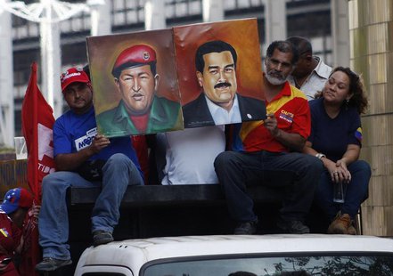 Supporters of Venezuela's President-elect Nicolas Maduro hold his portrait with one of Hugo Chavez during a demonstration in his favor, in C Supporters of Venezuela's President-elect Nicolas Maduro hold his portrait with one of Hugo Chavez during a demonstration in his favor, in C