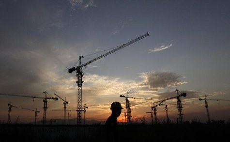 A worker walks past a residential construction site as the sun sets behind construction cranes on the outskirts of Beijing August 18, 2011. A worker walks past a residential construction site as the sun sets behind construction cranes on the outskirts of Beijing August 18, 2011.