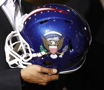 U.S. President Barack Obama holds a football helmet with the Presidential seal given to him during his visit to Riddell manufacturing facili U.S. President Barack Obama holds a football helmet with the Presidential seal given to him during his visit to Riddell manufacturing facili