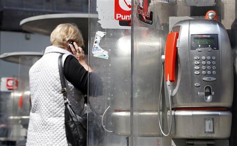 A woman walks near telephone booths in downtown Milan April 17, 2013. REUTERS/Stefano Rellandini A woman walks near telephone booths in downtown Milan April 17, 2013. REUTERS/Stefano Rellandini
