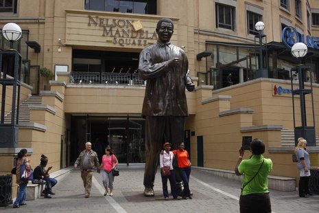 Visitors pose for photographs in front of a statue of former South African president Nelson Mandela in Sandton, Johannesburg March 30, 2013. Visitors pose for photographs in front of a statue of former South African president Nelson Mandela in Sandton, Johannesburg March 30, 2013.
