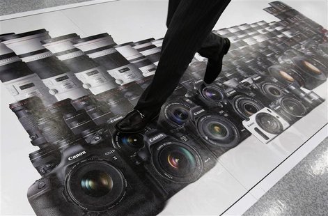 A man walks on an advertisement of Canon digital cameras at an electronics retail store in Tokyo April 23, 2013. Japan's Canon Inc said firs A man walks on an advertisement of Canon digital cameras at an electronics retail store in Tokyo April 23, 2013. Japan's Canon Inc said firs