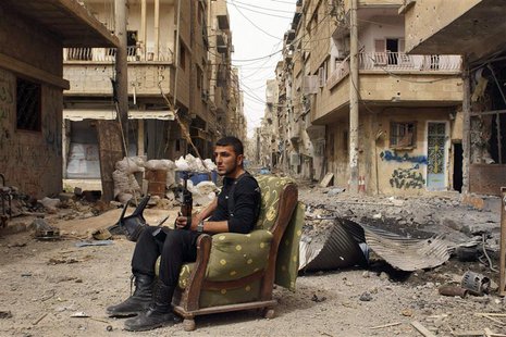 A member of the Free Syrian Army holds his weapon as he sits on a sofa in the middle of a street in Deir al-Zor, in this April 2, 2013 file A member of the Free Syrian Army holds his weapon as he sits on a sofa in the middle of a street in Deir al-Zor, in this April 2, 2013 file