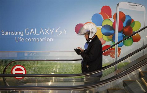 A motorcycle dispatch rider uses his smartphone next to an advertisement promoting Samsung Electronics Co Ltd's latest flagship smartphone G A motorcycle dispatch rider uses his smartphone next to an advertisement promoting Samsung Electronics Co Ltd's latest flagship smartphone G