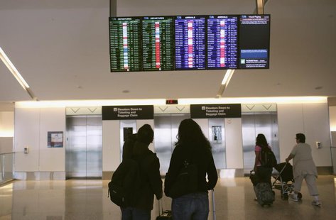 Airline passengers look at a flight status board at San Francisco International Airport in San Francisco, California April 22, 2013. REUTERS Airline passengers look at a flight status board at San Francisco International Airport in San Francisco, California April 22, 2013. REUTERS