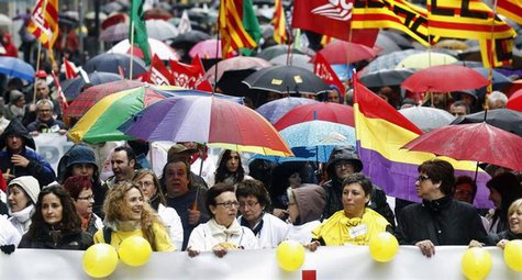 People hold umbrellas as they march with a banner during a protest against government austerity measures in Barcelona April 28, 2013. REUTER People hold umbrellas as they march with a banner during a protest against government austerity measures in Barcelona April 28, 2013. REUTER