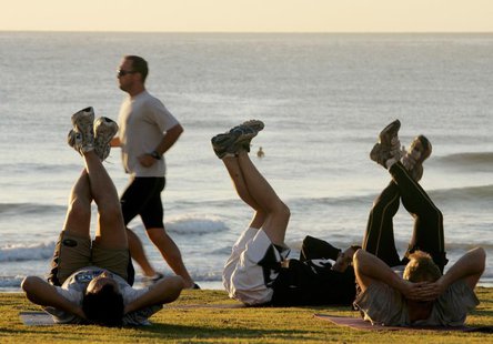 A jogger (2nd L) passes fitness enthusiasts performing stretching exercises after sunrise at Queenscliff Beach in Sydney on the first day of A jogger (2nd L) passes fitness enthusiasts performing stretching exercises after sunrise at Queenscliff Beach in Sydney on the first day of