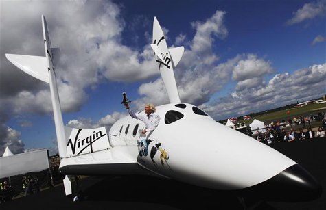 Entrepreneur Richard Branson waves a model of the LauncherOne cargo spacecraft from a window of an actual size model of SpaceShipTwo on disp Entrepreneur Richard Branson waves a model of the LauncherOne cargo spacecraft from a window of an actual size model of SpaceShipTwo on disp
