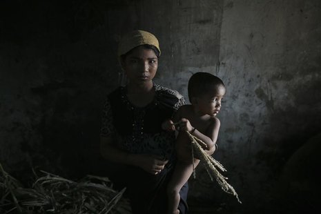 Hla Hla May, a Rohingya Muslim woman displaced by violence, holds her one year old daughter Roshan at a former rubber factory that now serve Hla Hla May, a Rohingya Muslim woman displaced by violence, holds her one year old daughter Roshan at a former rubber factory that now serve