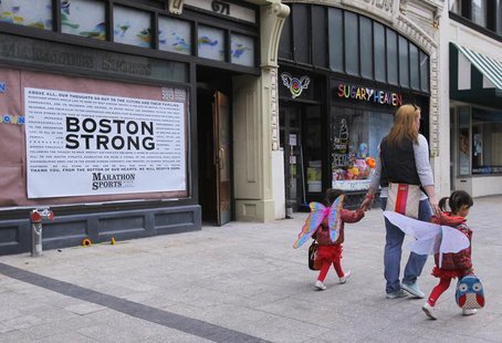 A woman walks her children wearing wings in front of the site of the first explosion on Boylston Street after the street reopened to the pub A woman walks her children wearing wings in front of the site of the first explosion on Boylston Street after the street reopened to the pub