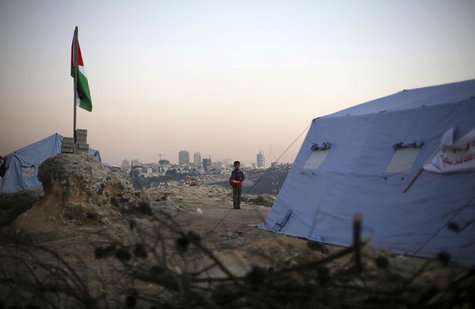 A boy stands near a Palestinian flag placed near newly-erected tents in the West Bank village of Beit Iksa, between Ramallah and Jerusalem J A boy stands near a Palestinian flag placed near newly-erected tents in the West Bank village of Beit Iksa, between Ramallah and Jerusalem J