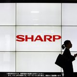 A woman walks past the Sharp Corp's Logo at a train station in Tokyo March 6, 2013. REUTERS/Yuya Shino