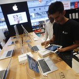 A salesperson unpacks an Apple iPad Mini to test it for a customer in the Apple specialty section of a Croma retail store in Mumbai February