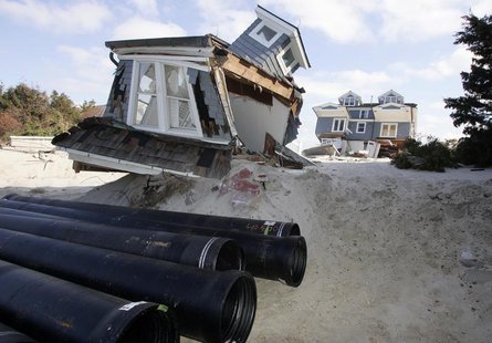 Sewer line pipes waiting for installation are stacked near parts of a house that broke off and washed up near the street in Mantoloking, New Sewer line pipes waiting for installation are stacked near parts of a house that broke off and washed up near the street in Mantoloking, New