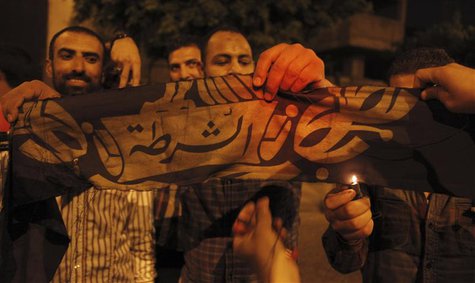 Islamist protesters shout slogans and burn a flag with the word " Police" on it, after they took it down and erected several al Qaeda flags Islamist protesters shout slogans and burn a flag with the word " Police" on it, after they took it down and erected several al Qaeda flags