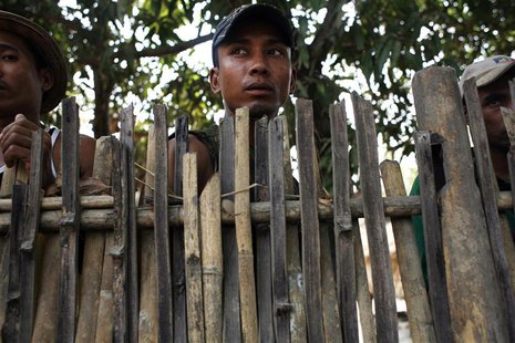 Muslim men from Win Kite village look from behind the fence which residents built to protect their village from mob attacks May 2, 2013. REU Muslim men from Win Kite village look from behind the fence which residents built to protect their village from mob attacks May 2, 2013. REU
