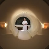 A cancer patient is seen through the tube of a magnetic resonance imaging scanner as she prepares to enter the MRI machine for an examinatio