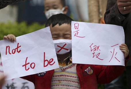 A boy wearing a mask holds papers as he protests against a planned refinery which produces the chemical paraxylene (PX), at a square in Kunm A boy wearing a mask holds papers as he protests against a planned refinery which produces the chemical paraxylene (PX), at a square in Kunm
