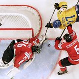 Switzerland's goalie Martin Gerber (L) and Severin Blindenbacher (R) fight for the puck with Sweden's Jimmie Ericsson during their 2013 IIHF