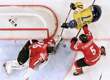 Switzerland's goalie Martin Gerber (L) and Severin Blindenbacher (R) fight for the puck with Sweden's Jimmie Ericsson during their 2013 IIHF Switzerland's goalie Martin Gerber (L) and Severin Blindenbacher (R) fight for the puck with Sweden's Jimmie Ericsson during their 2013 IIHF