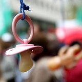 A baby pacifier hangs from an umbrella as part of the props used by union workers in a non-profit sector march in Brussels December 2, 2005.