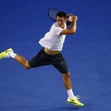 Bernard Tomic of Australia hits a return to Roger Federer of Switzerland during their men's singles match at the Australian Open tennis tour