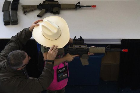 A man adjusts a girl's hat before she takes aim with an airsoft gun during the NRA Youth Day at the National Rifle Association's annual meet A man adjusts a girl's hat before she takes aim with an airsoft gun during the NRA Youth Day at the National Rifle Association's annual meet