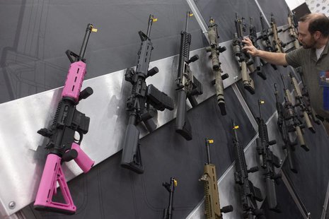 A pink assault rifle hangs among others at an exhibit booth at the George R. Brown convention center, the site for the National Rifle Associ A pink assault rifle hangs among others at an exhibit booth at the George R. Brown convention center, the site for the National Rifle Associ