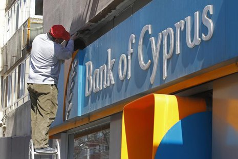 A worker paints a wall above a branch of Bank of Cyprus in Bucharest April 1, 2013. REUTERS/Bogdan Cristel A worker paints a wall above a branch of Bank of Cyprus in Bucharest April 1, 2013. REUTERS/Bogdan Cristel