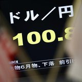 A monitor displaying the Japanese yen's exchange rate against the U.S. dollar is seen between the U.S. (L) and Japanese national flags at a 