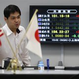 An employee of a foreign exchange trading company works next to a monitor displaying the Japanese yen's exchange rate against the U.S. dolla