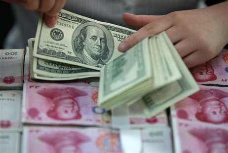 A bank clerk counts U.S. dollar banknotes on bundles of 100 Chinese yuan banknotes at a branch of a bank in Huaibei, Anhui province April 26 A bank clerk counts U.S. dollar banknotes on bundles of 100 Chinese yuan banknotes at a branch of a bank in Huaibei, Anhui province April 26