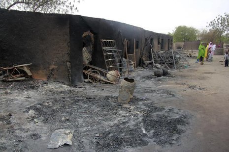 People walk past ashes in the aftermath of what Nigerian authorities said was heavy fighting between security forces and Islamist militants People walk past ashes in the aftermath of what Nigerian authorities said was heavy fighting between security forces and Islamist militants