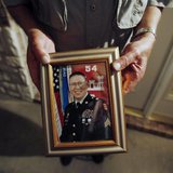 Wilburn Russell, 73, displays a portrait of his son, Sergeant John M. Russell, the Army sergeant who is accused of killing five fellow soldi