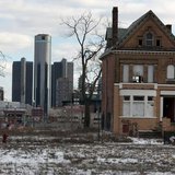 A vacant, boarded up house is seen in the once thriving Brush Park neighborhood with the downtown Detroit skyline behind it in Detroit, Mich