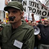 A high school teacher, dressed as soldier with his mouth taped shut, marches during a rally against their mobilisation and the government de
