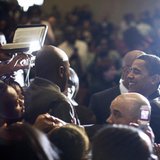 A churchgoer (L) tries to hand a Bible to US Democratic presidential candidate Barack Obama (R) to autograph as he greet worshippers followi