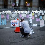 A woman kneels and cries in front of a memorial to the Boston Marathon bombings victims, at the barricades surrounding the scene in Boston, A woman kneels and cries in front of a memorial to the Boston Marathon bombings victims, at the barricades surrounding the scene in Boston,