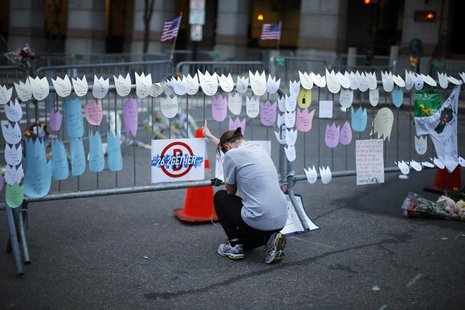 A woman kneels and cries in front of a memorial to the Boston Marathon bombings victims, at the barricades surrounding the scene in Boston, A woman kneels and cries in front of a memorial to the Boston Marathon bombings victims, at the barricades surrounding the scene in Boston,