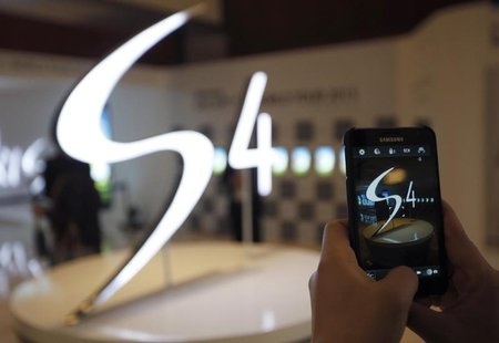 A man takes a photograph of a logo of Samsung Electronics Co Ltd's latest flagship smartphone S4 during its launch event at the company's he A man takes a photograph of a logo of Samsung Electronics Co Ltd's latest flagship smartphone S4 during its launch event at the company's he