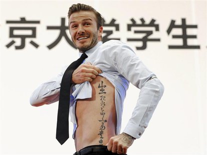 Former England captain David Beckham shows his tattoo after he was asked to by students at Peking University during his visit in Beijing in Former England captain David Beckham shows his tattoo after he was asked to by students at Peking University during his visit in Beijing in