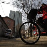 A woman rides her bicycle along an alley next to a residential compound in central Beijing, March 22, 2013. REUTERS/Petar Kujundzic