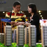A salesperson (R) talks to a customer behind models of a residential compound at a real estate exhibition in Wuxi, Jiangsu province May 18, A salesperson (R) talks to a customer behind models of a residential compound at a real estate exhibition in Wuxi, Jiangsu province May 18,