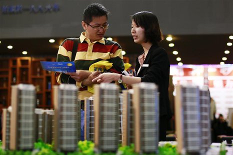 A salesperson (R) talks to a customer behind models of a residential compound at a real estate exhibition in Wuxi, Jiangsu province May 18, A salesperson (R) talks to a customer behind models of a residential compound at a real estate exhibition in Wuxi, Jiangsu province May 18,