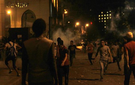 Protesters opposing Egyptian President Mohamed Mursi flee from tear gas fired by riot police during clashes along Qasr Al Nil bridge, which Protesters opposing Egyptian President Mohamed Mursi flee from tear gas fired by riot police during clashes along Qasr Al Nil bridge, which